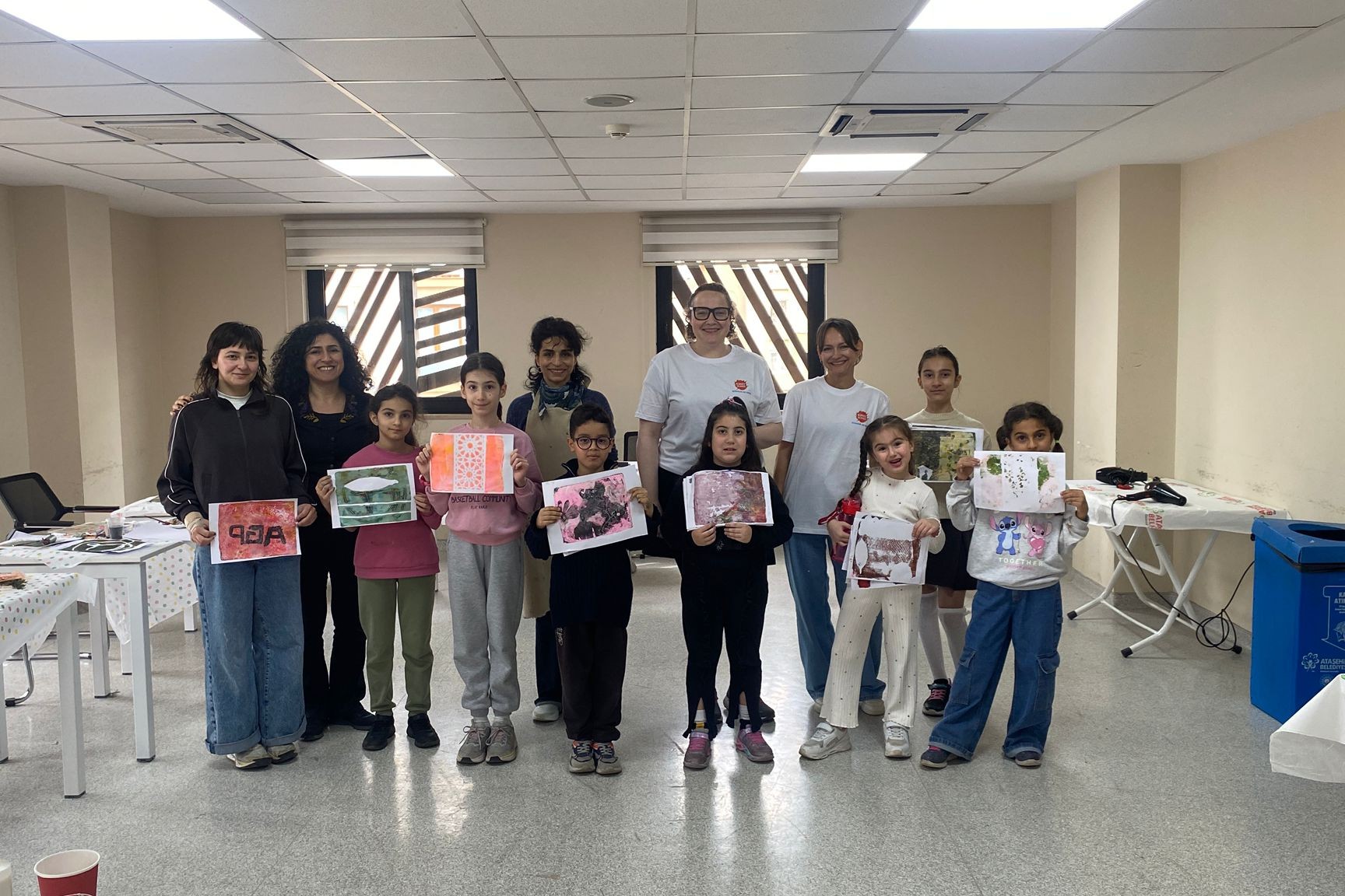 Mehrere Menschen in der Kunstschule Atasehir, die sich für ein Gruppenbild mit ihren zuvor entstandenen Werken aufgestellt haben.